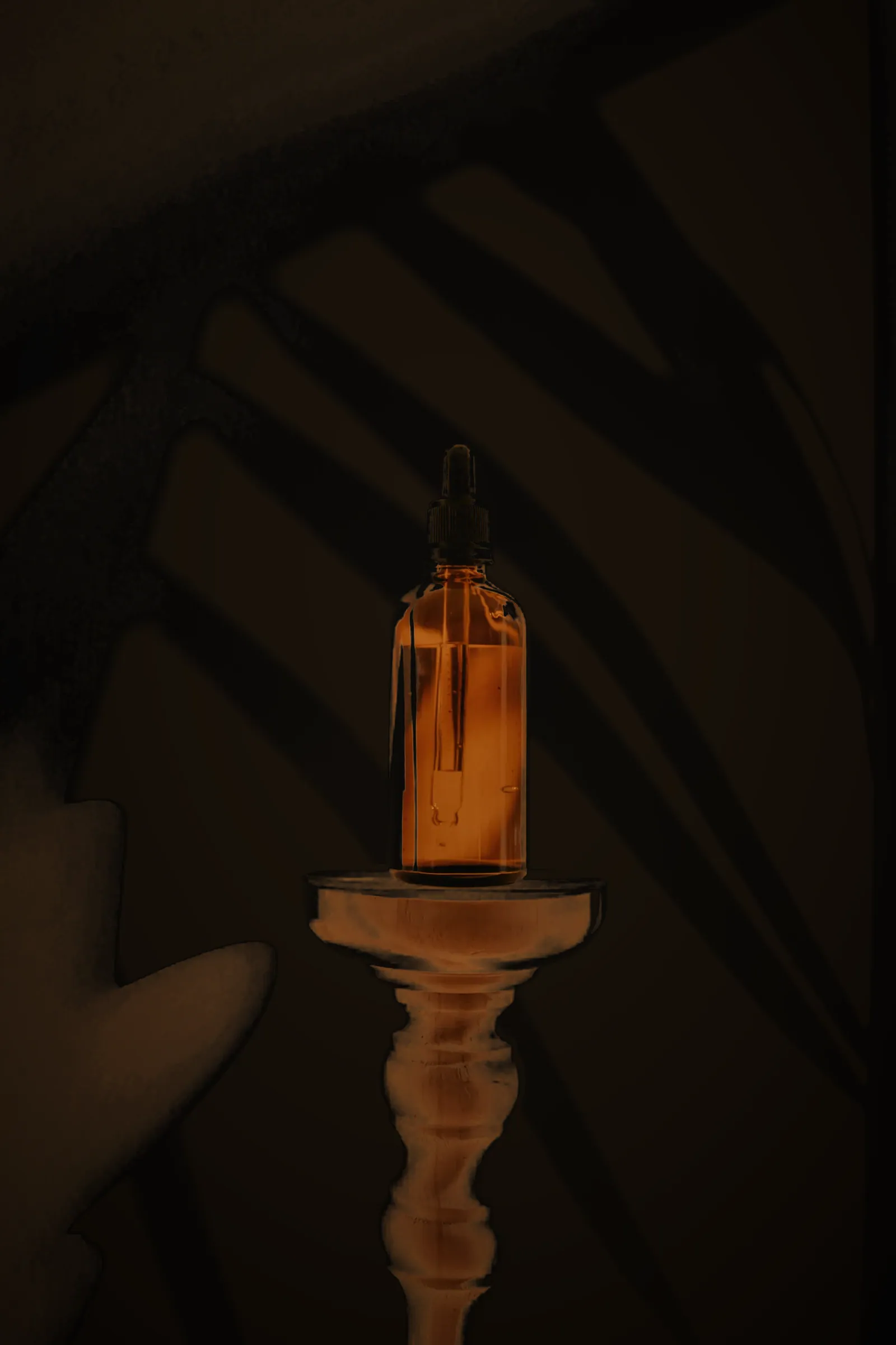 An amber glass vial lit from behind in a dark room